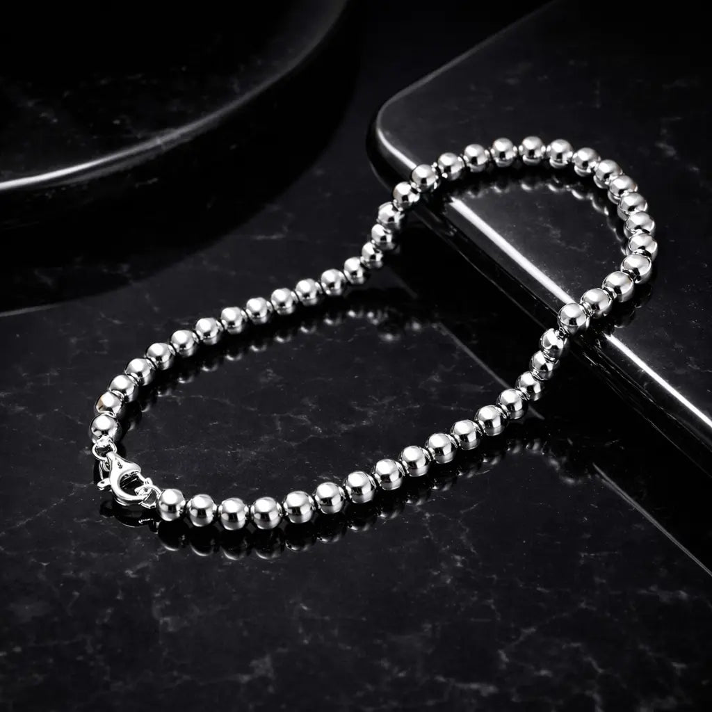 Geometric bracelet for men and women with silver electroplated beads, displayed on a black reflective surface