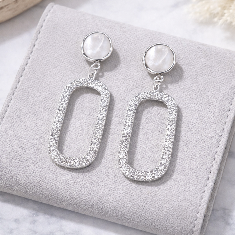 Silver earrings with oval designs on a gray jewelry box