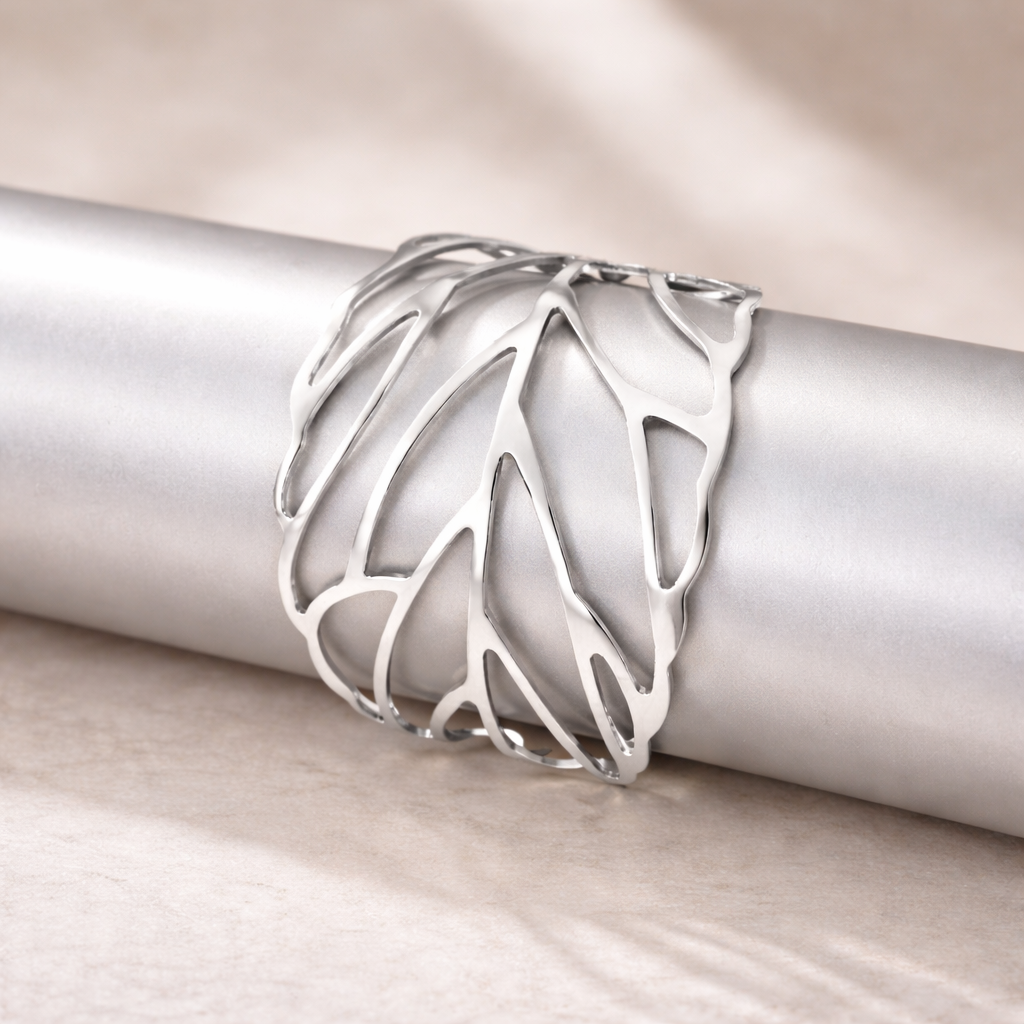 Silver ring with a leaf design on a metallic surface