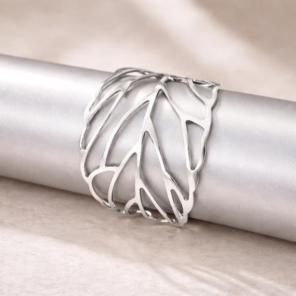 Silver ring with a leaf design on a metallic surface