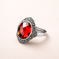 Silver ring with a red gemstone on a light background
