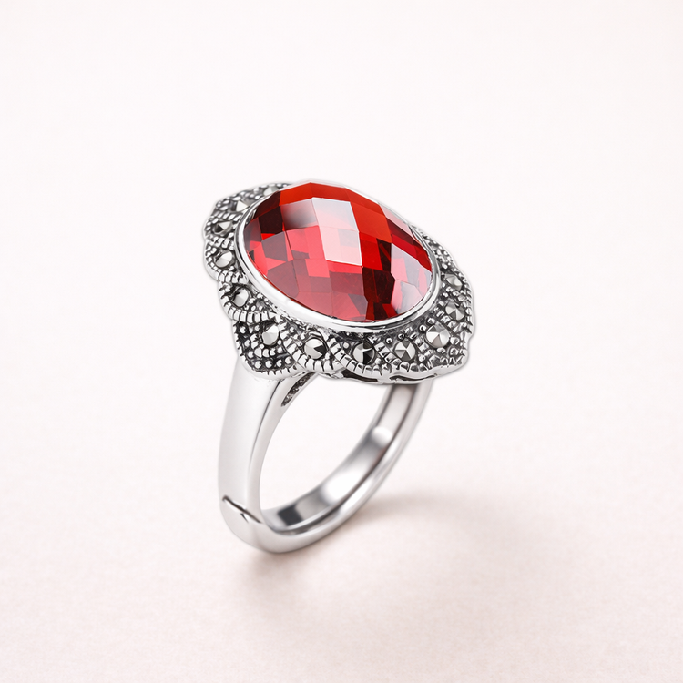 Silver ring with a red gemstone on a white background