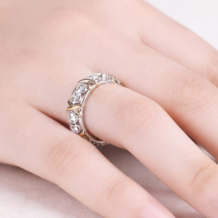 Silver ring with gemstones on a finger against a neutral background