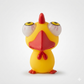 A yellow rubber toy chick with exaggerated white eyes, a red beak, red wattle, and red feet, photographed against a clean light gray studio background.