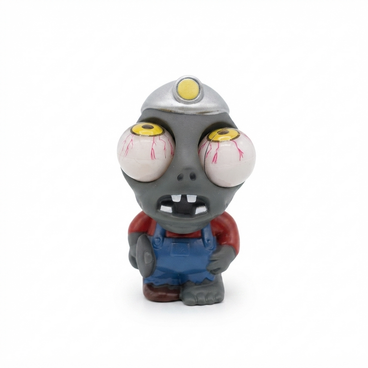 A small zombie miner figurine with large white eyeballs, red veins, a gray head, a silver helmet with a yellow light, a red shirt, and blue overalls, standing against a plain white background.