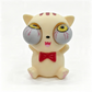 A cute, stylized cat figurine with exaggerated, bulging gray eyes, a red bow tie, and pink paw pads, photographed against a clean white background.