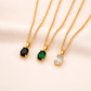 Three gold necklaces with gemstone pendants on a light pink background