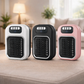 Three portable heaters in white, black, and pink on a surface with a blurred indoor background.