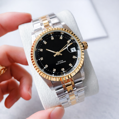 Two-tone watch with black face held by a hand on a light background