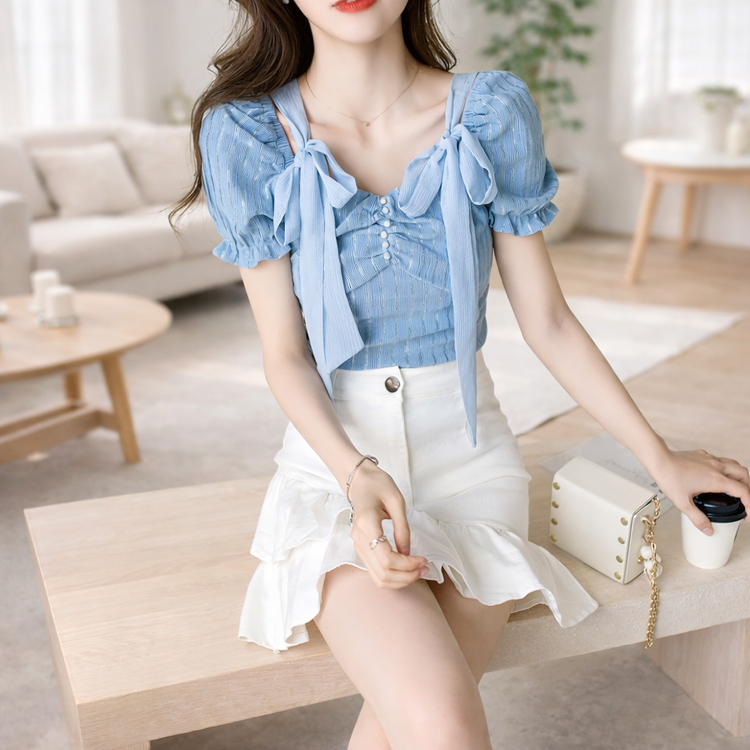 Woman in a blue top and white skirt sitting in a modern living room.