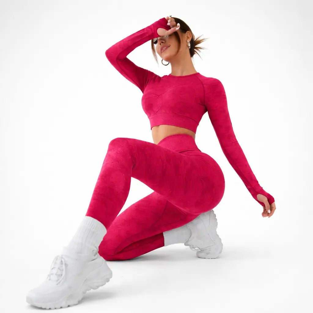 Nylon women's yoga suit for gym and pilates in pink, model wearing long-sleeve crop top and leggings, side view.