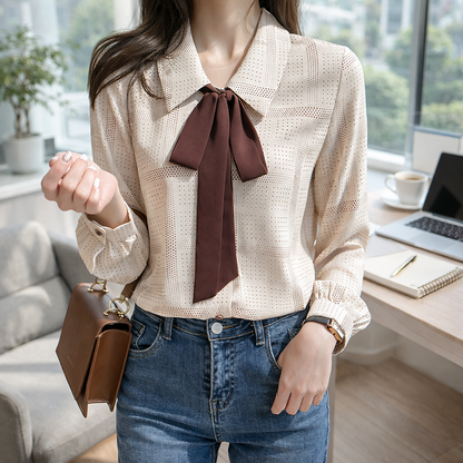 Woman wearing a beige blouse with a brown bow tie in an office setting