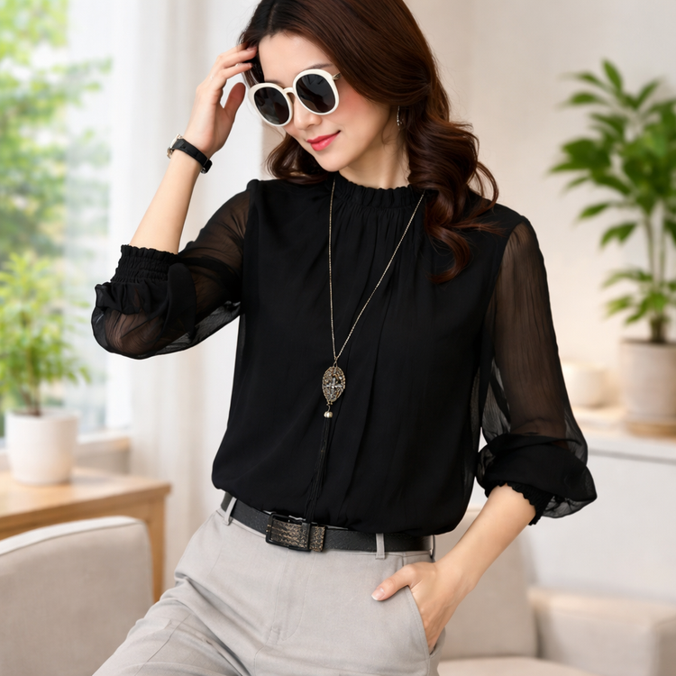 Woman wearing a black blouse with sheer sleeves in a living room setting