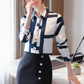 Woman wearing a blue and white patterned shirt with a black skirt in an office setting...