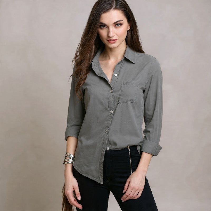 Woman wearing a gray button-up shirt against a beige background