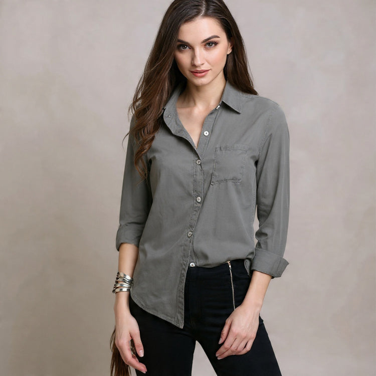 Woman wearing a gray button-up shirt against a beige background