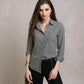 Woman wearing a gray button-up shirt against a beige background