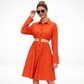 Woman wearing an orange dress with a belt on a white background