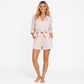 Woman wearing a light pink pajama set on a white background
