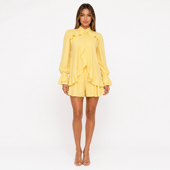Woman wearing a yellow dress with ruffled details on a white background