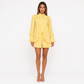 Woman wearing a yellow dress with ruffled details on a white background
