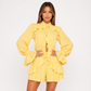 Woman wearing a yellow ruffled outfit on a white background