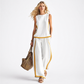 Woman wearing a white outfit with yellow accents, holding a straw bag on a white background