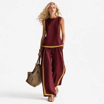 Woman wearing a burgundy outfit with gold trim, holding a textured bag on a white background