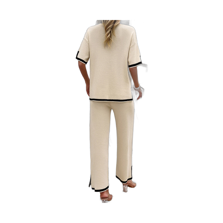 woman wearing beige two-piece set with black trim standing near white wall