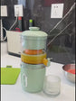 Person using a manual juicer to extract orange juice in a kitchen setting FRESH GREEN