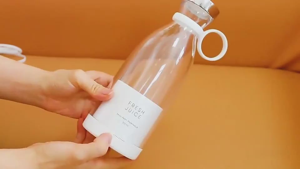 Pink bottle labeled 'Fresh Juice' with a glass of pink juice and grapefruit slices on a white surface. BLENDER