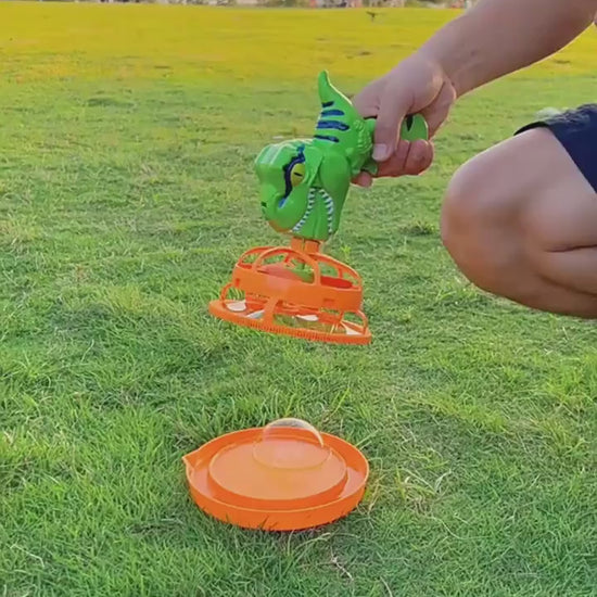 Green dinosaur-shaped bubble gun with bubbles in a grassy outdoor setting