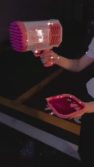 Pink bubble gun labeled 'Bazooka' with bubbles around on a wooden surface.