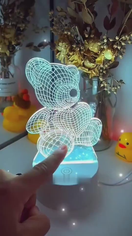 3D LED lamp shaped like a teddy bear with a heart balloon, glowing purple on a wooden surface. 3D Acrylic USB LED Night Lamp – Neon Sign

